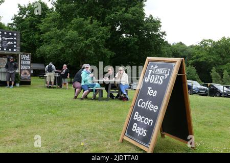 Les gens dandinent le café dans un lieu extérieur avec le tableau publicitaire au premier plan Banque D'Images