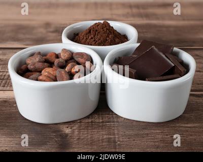 Morceaux de chocolat, poudre de cacao et haricots - produits pour la confiserie. Trois bols avec des ingrédients pleins d'antioxydants Banque D'Images