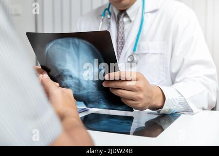 Concept médical et de soins de santé. Médecin expliquant les résultats de radiographie au patient lorsqu'il est assis à la table du bureau. Banque D'Images