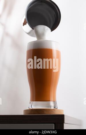 Un verre de thé au lait glacé et de mousse de lait. Versez la mousse de lait sur le thé au lait dans le verre. Banque D'Images
