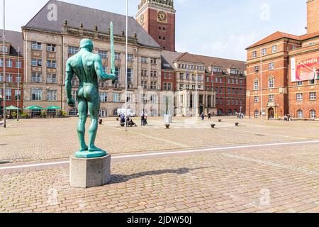 La statue de l'épée du porteur (Schwertträger) sur la place de Kieler Rathausplatz avec l'Hôtel de ville (Landeshauptstadt) et l'Opéra de Kiel Banque D'Images