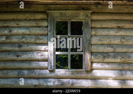 Fenêtre rectangulaire sur le mur d'une maison en rondins, arbres verts reflétés dans le verre. De la série fenêtre du monde. Banque D'Images