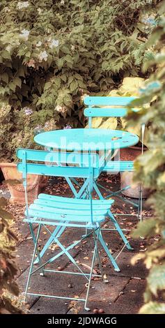 Deux chaises de cour et une table en métal bleu dans un paisible jardin privé avec des plantes vertes. Mobilier de jardin extérieur confortable et sièges Banque D'Images