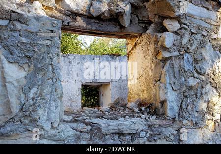 Ancienne maison cassée abandonnée avec d'épais murs en pierre qui s'émiettant. Ruines d'une maison rurale endommagée avec un cadre de fenêtre vide. Ancienne ferme aux intempéries avec Banque D'Images