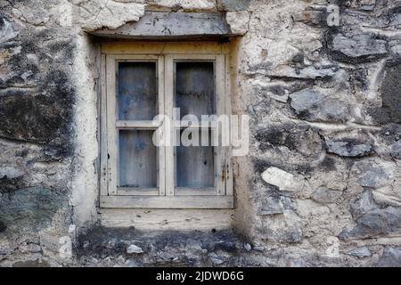 Gros plan d'une fenêtre en bois sur une ancienne maison dans un village. Extérieur de la vieille fenêtre sale et mur sur la ferme. Une petite fenêtre et pierre grise ou Banque D'Images