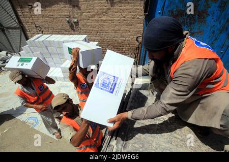 Peshawar, Afghanistan, 23 juin 2022. Des volontaires de la Fondation Al-Khidmat chargent des secours sur des camions alors que la Fondation Al-Khidmat (Jamat-e-Islami) a annoncé d'envoyer des tonnes de provisions et d'articles de secours pour le soutien des populations afghanes touchées par le tremblement de terre, à Peshawar jeudi, au 23 juin 2022. Banque D'Images