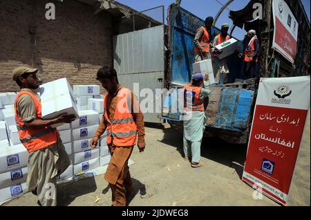 Peshawar, Afghanistan, 23 juin 2022. Des volontaires de la Fondation Al-Khidmat chargent des secours sur des camions alors que la Fondation Al-Khidmat (Jamat-e-Islami) a annoncé d'envoyer des tonnes de provisions et d'articles de secours pour le soutien des populations afghanes touchées par le tremblement de terre, à Peshawar jeudi, au 23 juin 2022. Banque D'Images