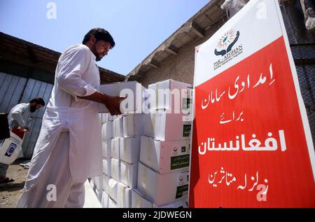 Peshawar, Afghanistan, 23 juin 2022. Des volontaires de la Fondation Al-Khidmat chargent des secours sur des camions alors que la Fondation Al-Khidmat (Jamat-e-Islami) a annoncé d'envoyer des tonnes de provisions et d'articles de secours pour le soutien des populations afghanes touchées par le tremblement de terre, à Peshawar jeudi, au 23 juin 2022. Banque D'Images