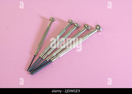 Différentes mini pour les travaux délicats sur les plus petites vis dans l'électronique et sur fond rose clair Banque D'Images