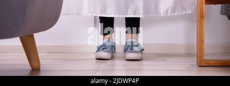 La section basse d'un Girl's pieds derrière le rideau sur plancher de bois franc Banque D'Images