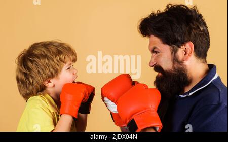 Enfant dans l'entraînement de gants de boxe avec entraîneur. Formateur enseigner à l'enfant. Perforation. Prêt pour l'arrosage Banque D'Images