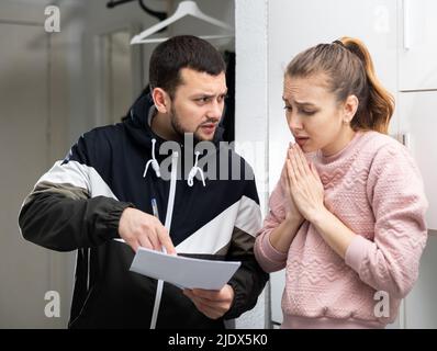 Femme frustrée parlant à la dette collectrice à la maison Banque D'Images