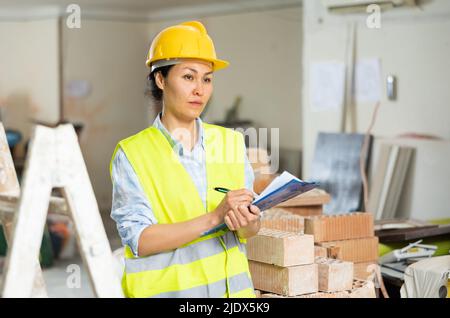 Femme prenant des notes sur le chantier de construction intérieur Banque D'Images