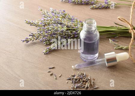 Récipients en verre avec essence de lavande avec bouquets de pointes autour sur bois dans une pièce de près. Vue avant. Composition horizontale. Banque D'Images