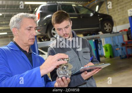 Avec moniteur étudiant la réparation d'une voiture pendant l'apprentissage Banque D'Images