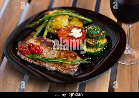 Filet de bœuf frit avec légumes et cassis sur fond de bois Banque D'Images