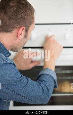 homme changeant la température du four domestique Banque D'Images