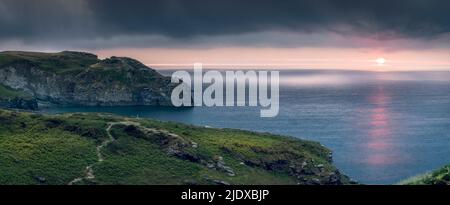 Après une chaude journée d'été en juin, les nuages commencent à s'accumuler et à s'assombrir au-dessus du promontoire dans la Cornouailles du Nord tandis que le soleil se couche sur le sentier côtier Banque D'Images