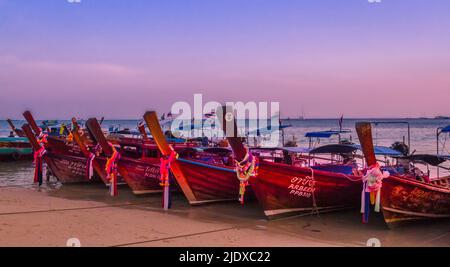 Des bateaux Kho Phi long se sont alignés sur la plage pour la nuit. Coucher de soleil dans le ciel et plage en premier plan. Banque D'Images