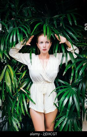 Portrait d'une jeune belle femme posant au milieu de plantes tropicales Banque D'Images