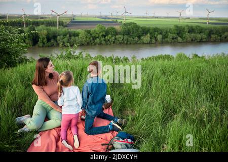 Mère avec fille et fils regardant les éoliennes sur le terrain le week-end Banque D'Images