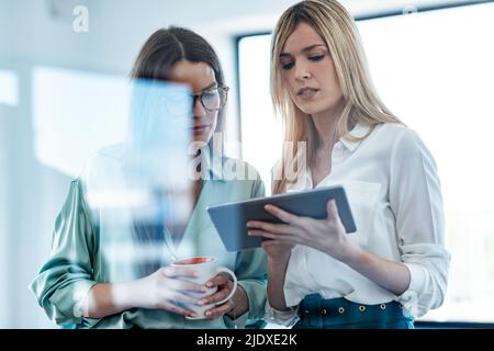 Une femme d'affaires partage ses idées avec ses collègues par rapport à une tablette au bureau Banque D'Images