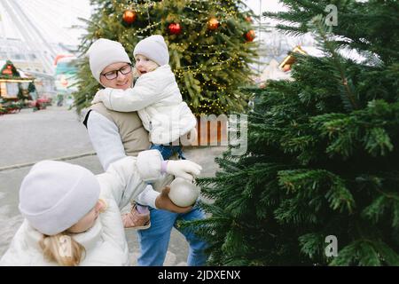 Père et filles mettant l'ornement de Noël sur l'arbre Banque D'Images