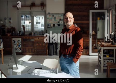 Homme d'affaires souriant debout avec les mains dans les poches au bureau Banque D'Images