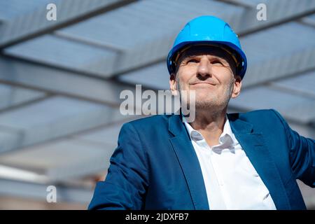 Homme d'affaires souriant portant un casque de sécurité sur le chantier de construction Banque D'Images