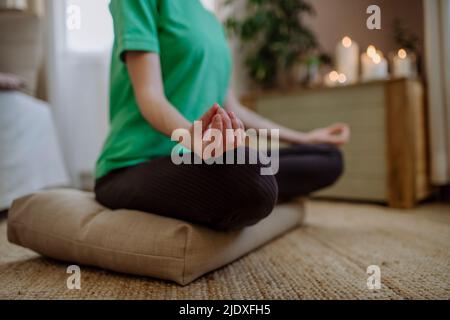 Femme pratiquant la position de lotus à la maison Banque D'Images