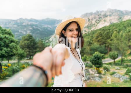 Jeune homme tenant la main d'une amie heureuse devant la chaîne de montagnes Banque D'Images