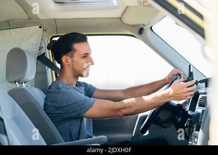 Homme souriant et charmant utilisant un smartphone assis dans une camionnette Banque D'Images