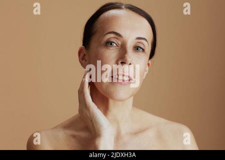 femme moderne d'âge moyen posant isolée sur beige. Banque D'Images