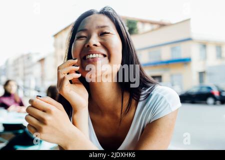 Jeune femme gaie avec les yeux fermés assis au café-terrasse Banque D'Images