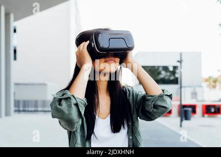 Jeune femme aux cheveux noirs portant un simulateur de réalité virtuelle Banque D'Images