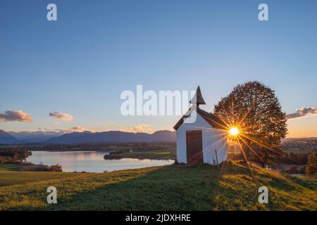 Allemagne, Bavière, Aidling, Mesnerhauskapelle au coucher du soleil avec le lac Riegsee en arrière-plan Banque D'Images