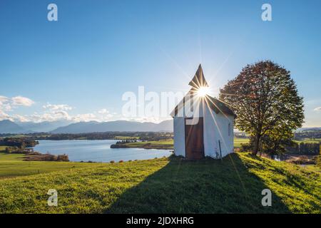 Allemagne, Bavière, Aidling, Mesnerhauskapelle au coucher du soleil avec le lac Riegsee en arrière-plan Banque D'Images