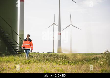 Ingénieur marchant devant les éoliennes sur le terrain Banque D'Images