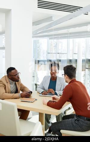 Hommes d'affaires regardant un collègue discuter de plan assis à la table au bureau Banque D'Images