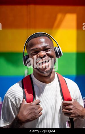 Un jeune homme heureux qui écoute de la musique avec un casque sans fil par beau temps Banque D'Images