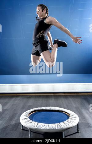 Jeune gymnaste sautant sur petit trampoline Banque D'Images