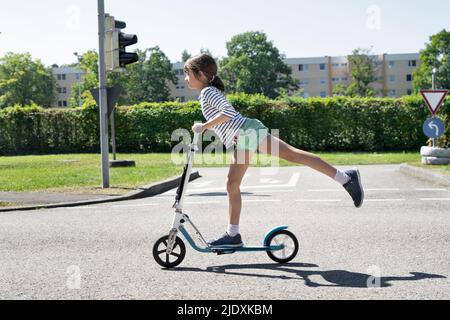 Fille de scooter de poussée sur le parcours de circulation Banque D'Images