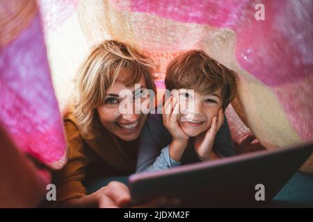 Mère heureuse avec son fils allongé sous une couverture à la maison Banque D'Images