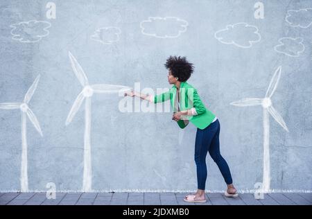 Femme expliquant les éoliennes peintes sur le mur Banque D'Images