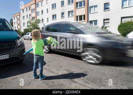 Garçon tenant un cône d'école sur la route s'arrêtant pour la voiture de vitesse Banque D'Images