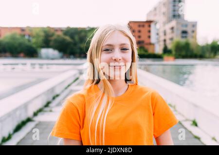 Bonne fille aux cheveux blonds portant un t-shirt orange Banque D'Images