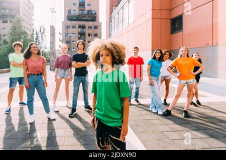 Garçon avec une coiffure afro debout devant des amis Banque D'Images