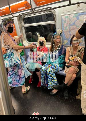 Le train F pour Coney Island est plein de demoiselles colorées et de personnes avec d'autres robes colorées sur leur chemin à la Mermaid Parade annuelle ouvrant la saison d'été à Brooklyn, New York. Banque D'Images