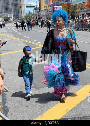 Une femme aux couleurs vives, avec un jeune fils aux pieds, se promène sur Surf Avenue le jour de la Mermaid Parade à Coney Island, Brooklyn, New York. Banque D'Images