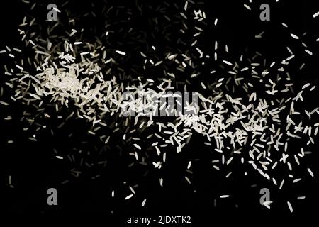 Tas de riz cru sur fond sombre. Explosion de riz blanc brut. Farcir le riz sur fond noir Banque D'Images